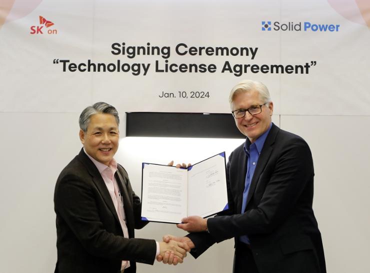 The Korean battery maker's Chief Commercial Officer Sung Min-suk, left, shakes hands with John Van Scoter, president and CEO of U.S. battery startup Solid Power, after signing a technology transfer agreement at the Las Vegas Convention Center in the United States, Jan. 10. Courtesy of SK On 